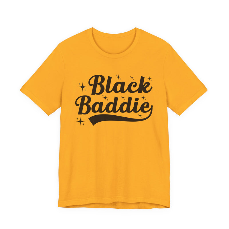 White t-shirt with gold bold statement lettering reading BLACK BADDIE, front flat-lay view.