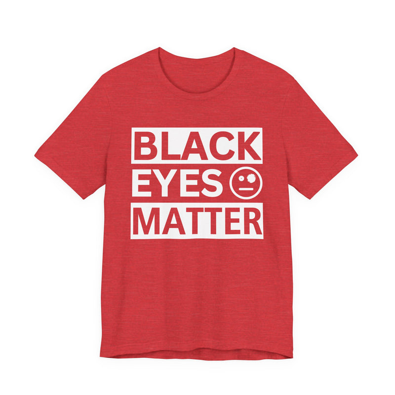 Heather Red t-shirt with ‘BLACK EYES MATTER’ in boxed block lettering with a smiley-face eye icon graphic in light-contrast print, front flat-lay mockup view