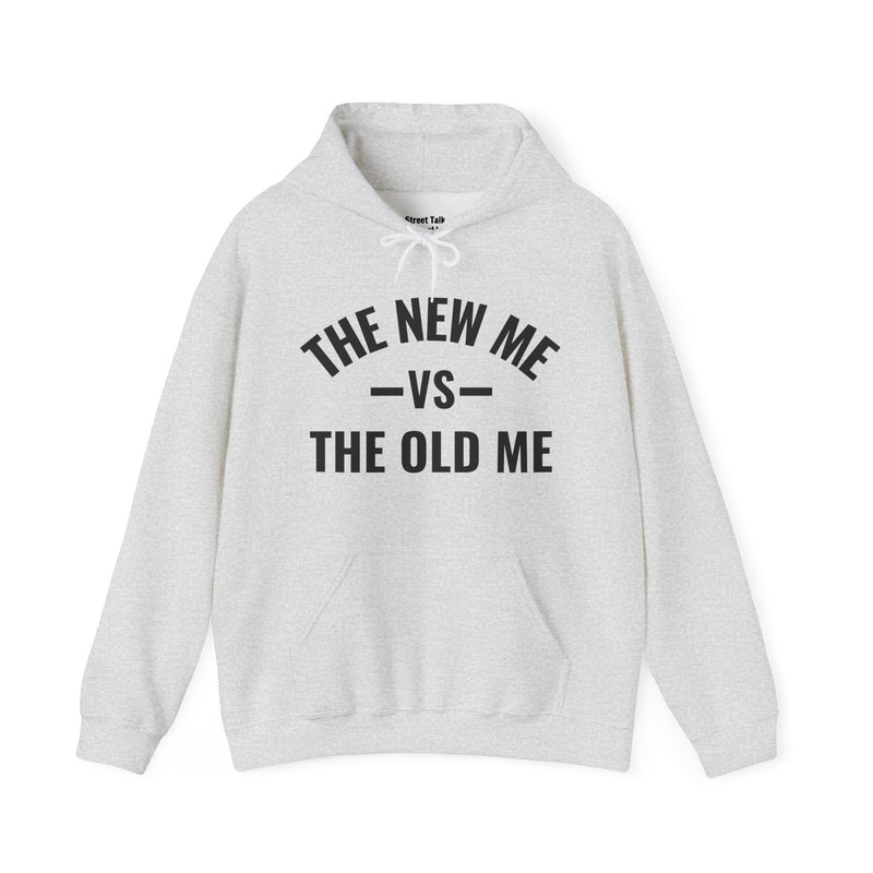 Ash hoodie with dark bold versus-style lettering reading THE NEW ME VS THE OLD ME, front flat-lay view.