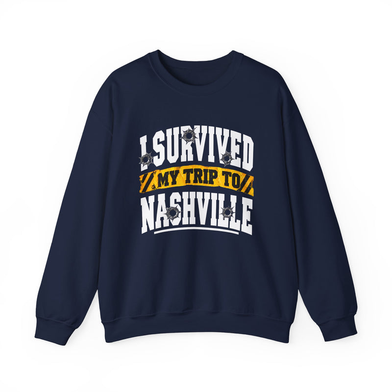Navy sweatshirt with white block lettering reading I SURVIVED MY TRIP TO NASHVILLE, with bullet-hole accents and a yellow caution-tape banner, front flat-lay view.