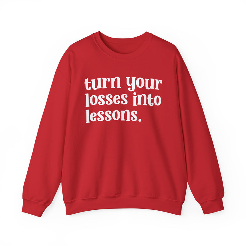 Red crewneck sweatshirt with white "turn your losses into lessons." lettering, front view.