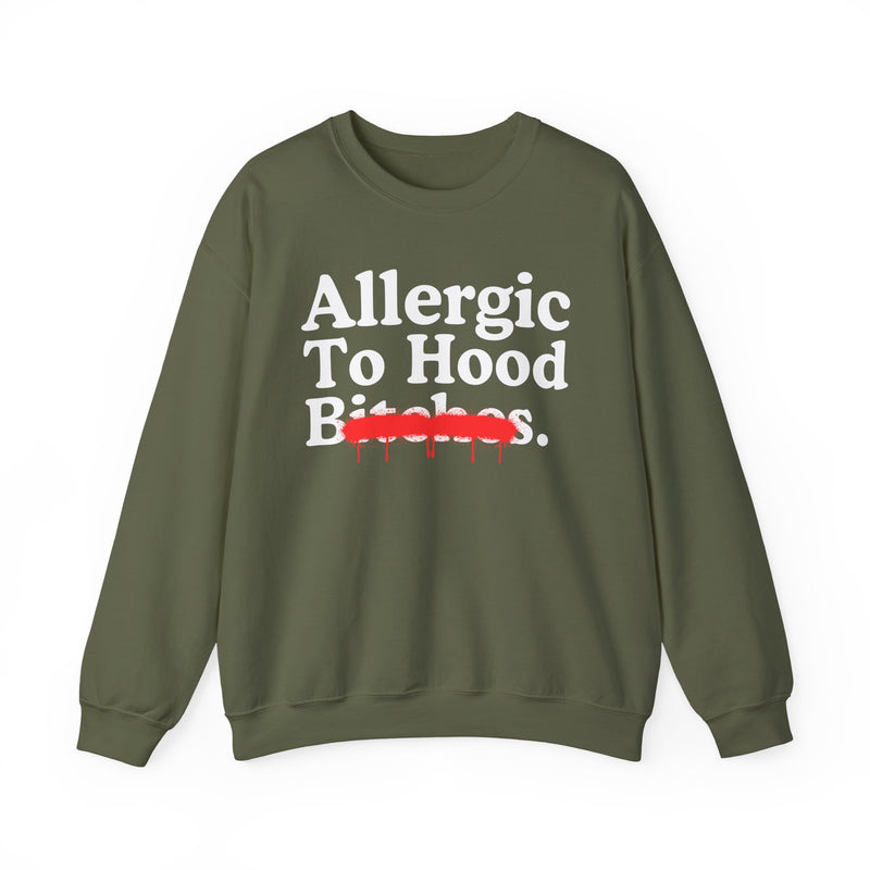 Brown sweatshirt with white serif lettering reading Allergic To Hood Bitches, crossed by a red dripping strikethrough, front flat-lay view.