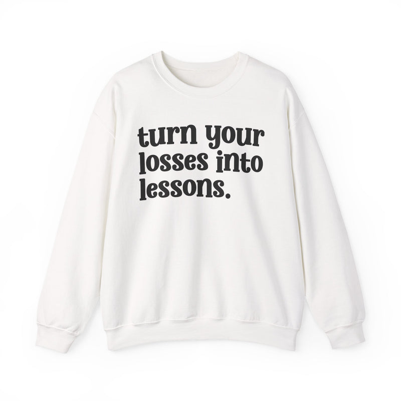 White crewneck sweatshirt with black "turn your losses into lessons." lettering, front view.