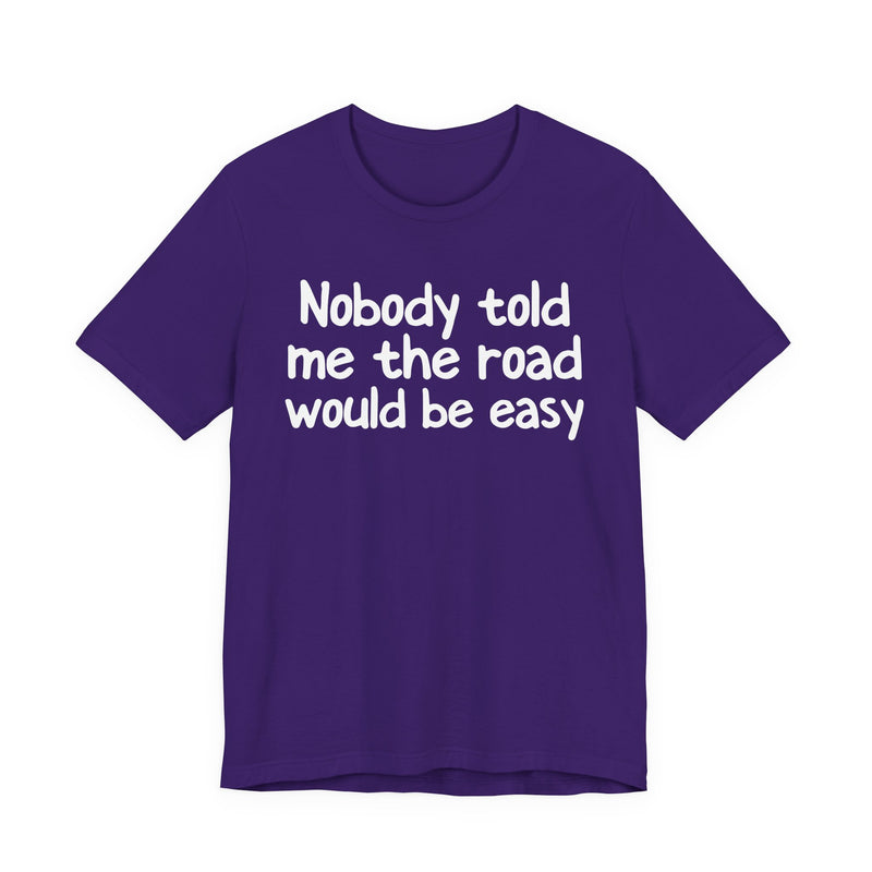 T-Shirt with text design reading “NOBODY TOLD ME THE ROAD WOULD BE EASY”, front view