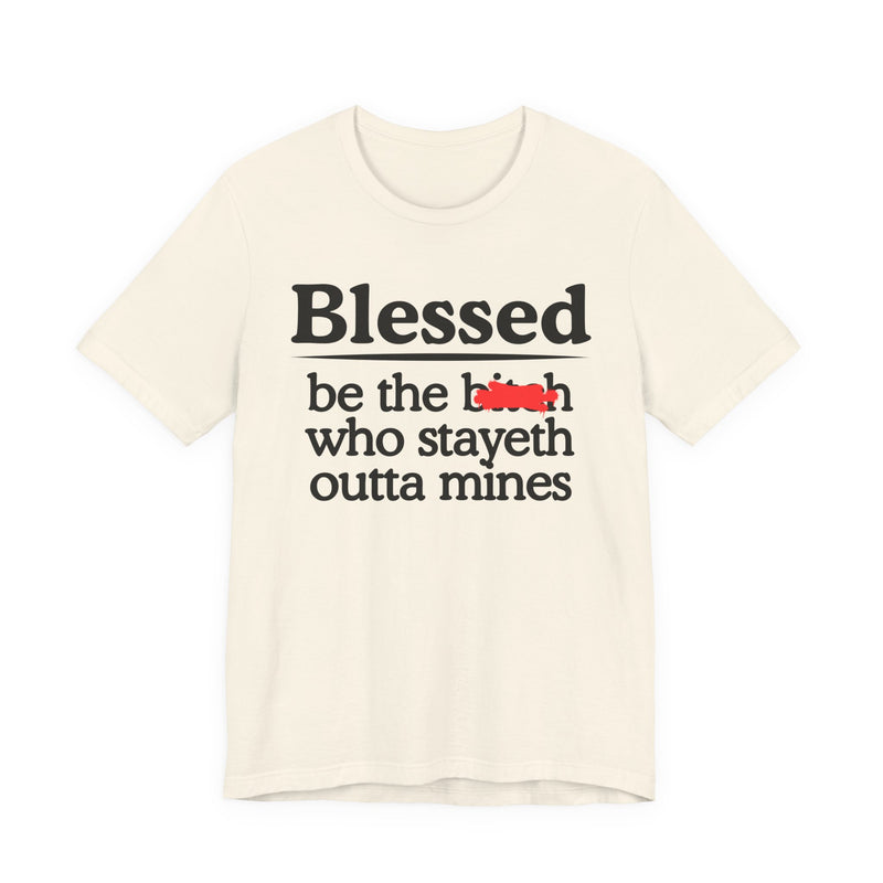Soft Cream tee with black serif lettering reading "Blessed be the b—h who stayeth outta mines", front flat-lay view, with a red redaction mark over the middle word.