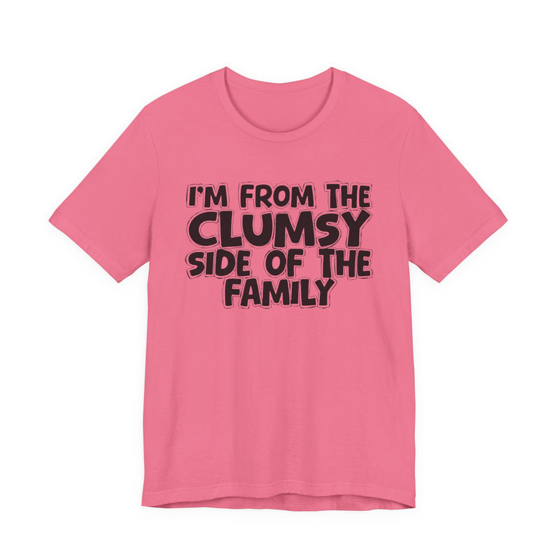 Charity Pink t-shirt, printed with the "I'M FROM THE CLUMSY SIDE OF THE FAMILY" statement in bold outlined bubble lettering, front flat-lay view.