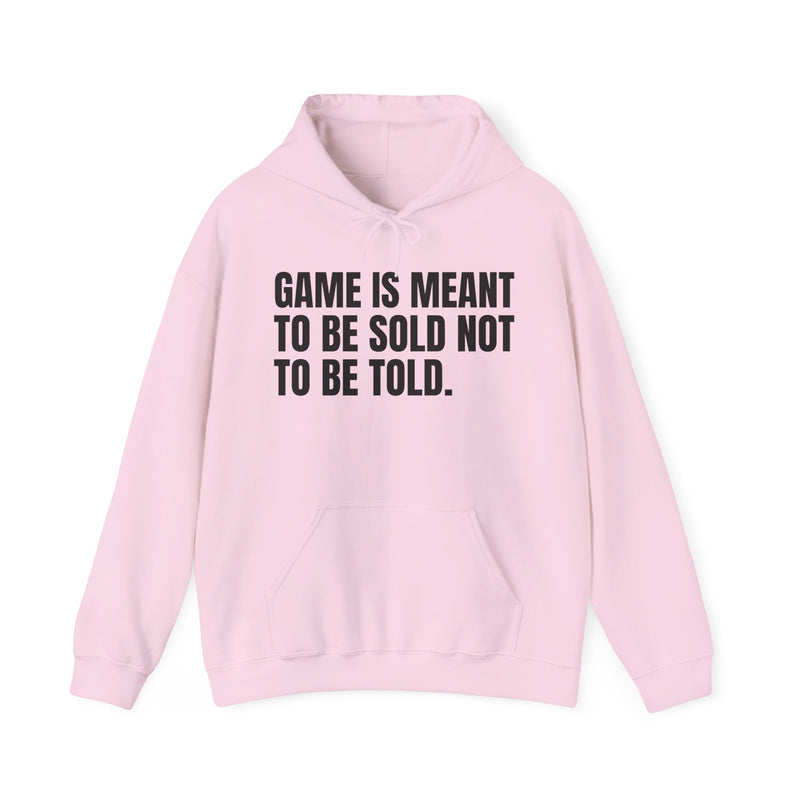 Light Pink hoodie with black condensed block lettering reading "GAME IS MEANT TO BE SOLD NOT TO BE TOLD.", front flat-lay view.