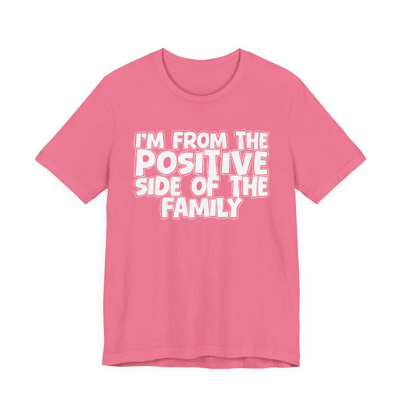 Charity Pink t-shirt with white outlined bubble lettering reading 'I'M FROM THE POSITIVE SIDE OF THE FAMILY', front flat-lay view.