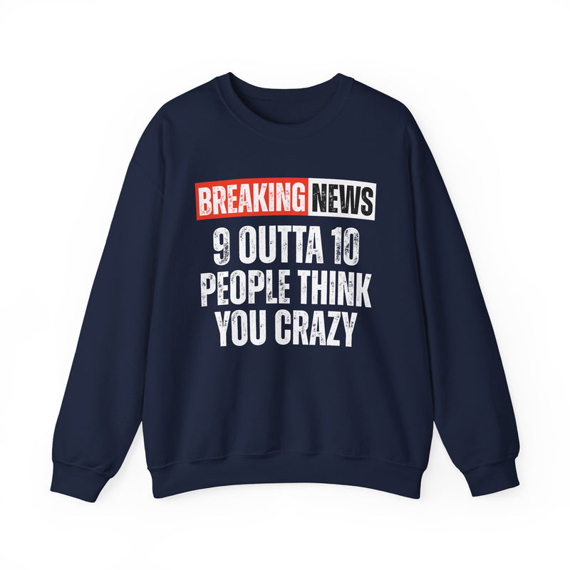 BREAKING NEWS banner graphic with distressed headline text '9 OUTTA 10 PEOPLE THINK YOU CRAZY' - sweatshirt in charcoal, front view, product mockup on white background