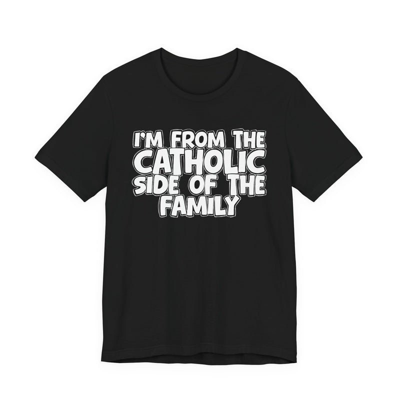 Black t-shirt with white outlined bubble lettering reading 'I'M FROM THE CATHOLIC SIDE OF THE FAMILY', front flat-lay view.