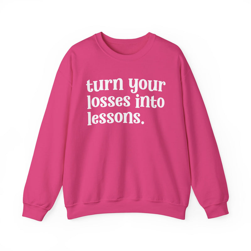 Hot pink crewneck sweatshirt with white "turn your losses into lessons." lettering, front view.