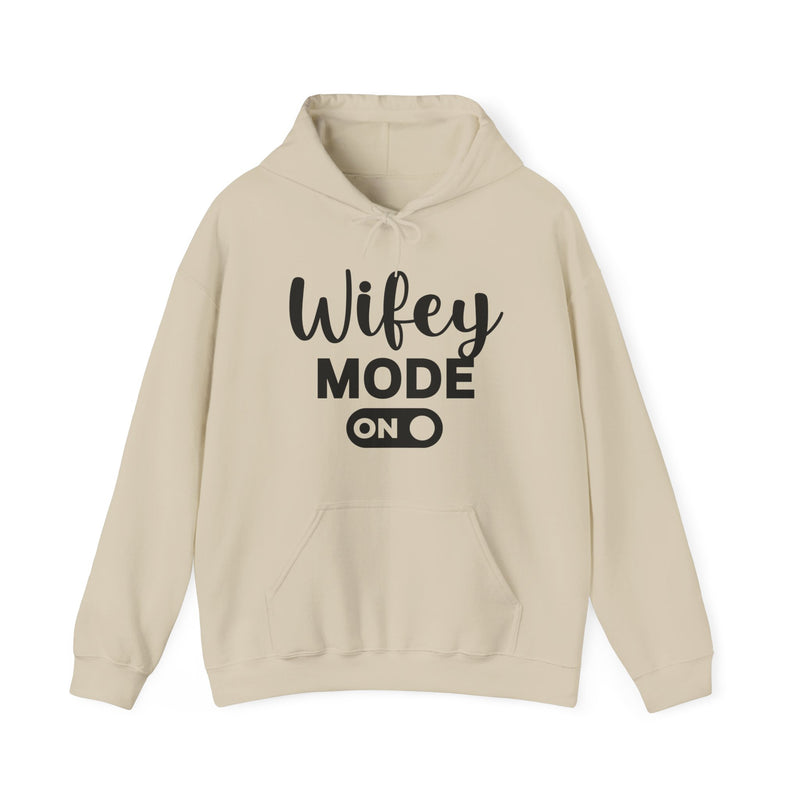 Sand hoodie with black bold block lettering reading WIFEY MODE ON, front flat-lay view.