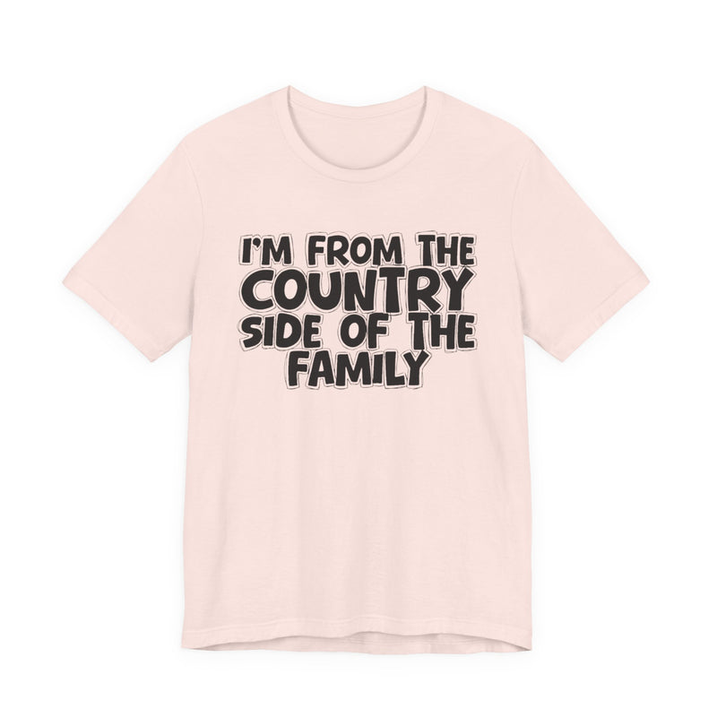 Soft Pink t-shirt with white outlined bubble lettering reading 'I'M FROM THE COUNTRY SIDE OF THE FAMILY', front flat-lay view.