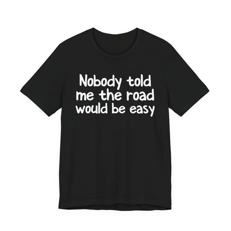 T-Shirt with text design reading “NOBODY TOLD ME THE ROAD WOULD BE EASY”, front view