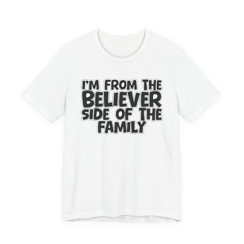 White t-shirt with white outlined bubble lettering reading 'I'M FROM THE BELIEVER SIDE OF THE FAMILY', front flat-lay view.