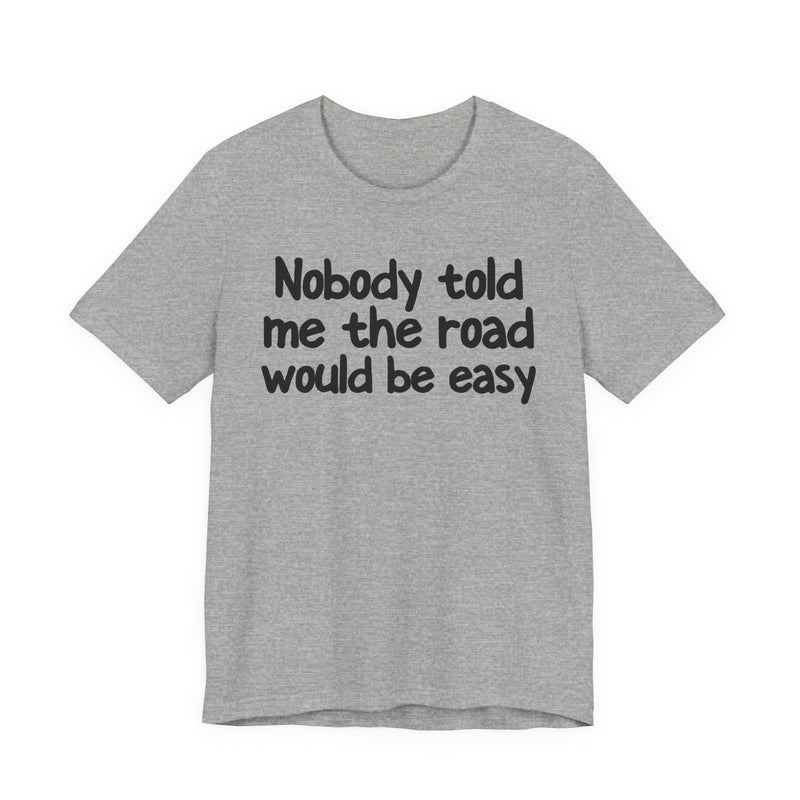 T-Shirt with text design reading “NOBODY TOLD ME THE ROAD WOULD BE EASY”, front view