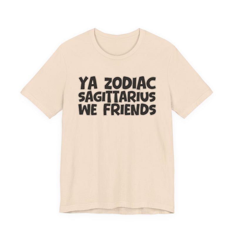 Soft Cream t-shirt with black 'YA ZODIAC SAGITTARIUS WE FRIENDS' cartoon bubble lettering, front flat-lay view.