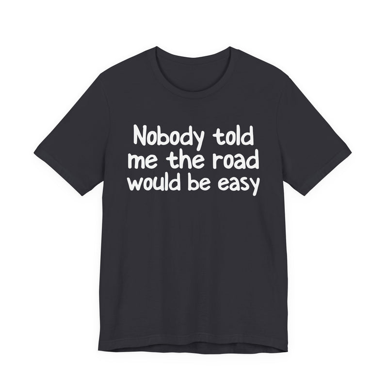 T-Shirt with text design reading “NOBODY TOLD ME THE ROAD WOULD BE EASY”, front view