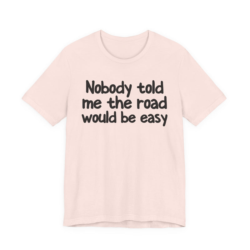 T-Shirt with text design reading “NOBODY TOLD ME THE ROAD WOULD BE EASY”, front view