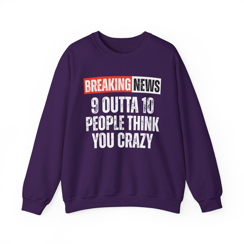 BREAKING NEWS banner graphic with distressed headline text '9 OUTTA 10 PEOPLE THINK YOU CRAZY' - sweatshirt in charcoal, front view, product mockup on white background