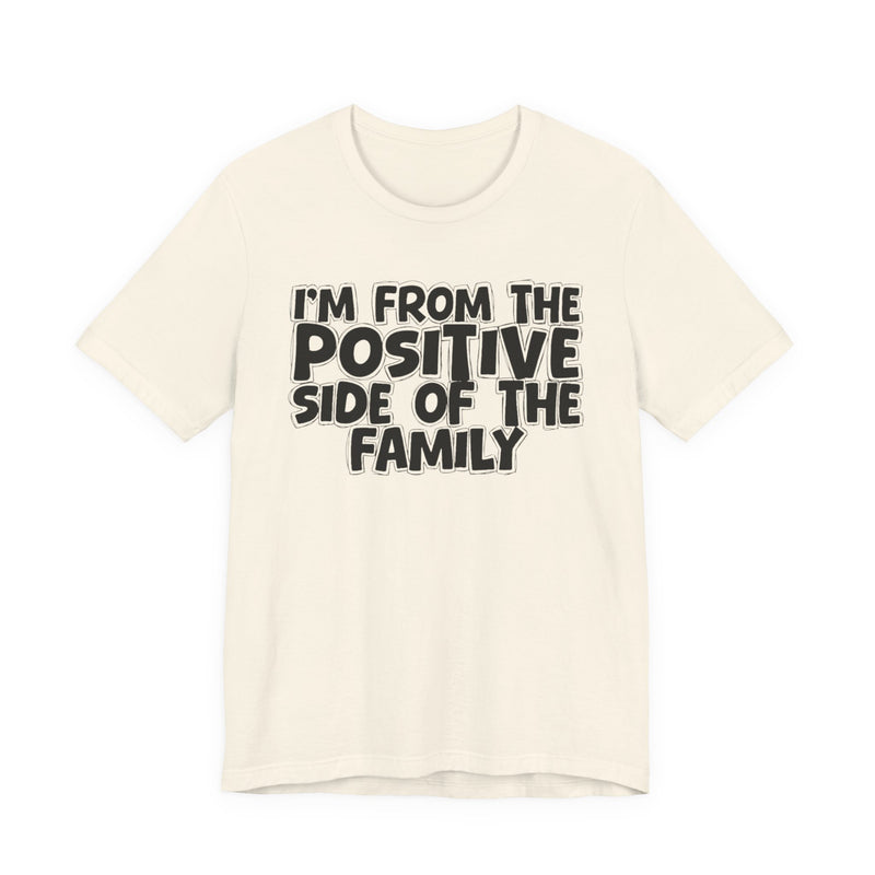 Natural t-shirt with white outlined bubble lettering reading 'I'M FROM THE POSITIVE SIDE OF THE FAMILY', front flat-lay view.