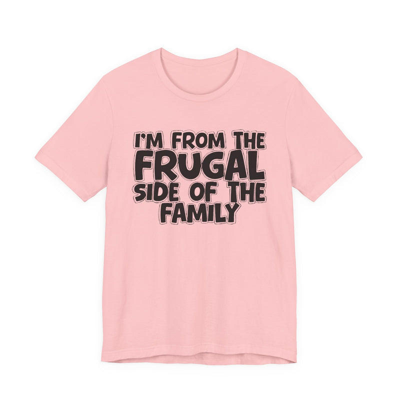 Soft Pink t-shirt with 'I'M FROM THE FRUGAL SIDE OF THE FAMILY' in black hand-drawn bubble lettering on the chest, front flat-lay mockup view.