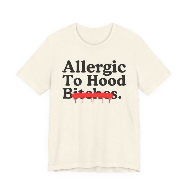 Natural T-Shirt with serif lettering reading Allergic To Hood Bitches, crossed by a red dripping strikethrough, front flat-lay view.