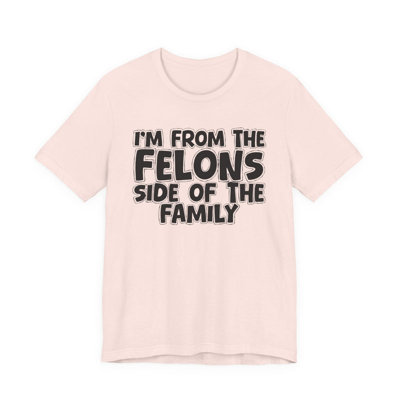 Soft Pink t-shirt with white outlined bubble lettering reading 'I'M FROM THE FELONS SIDE OF THE FAMILY', front flat-lay view.