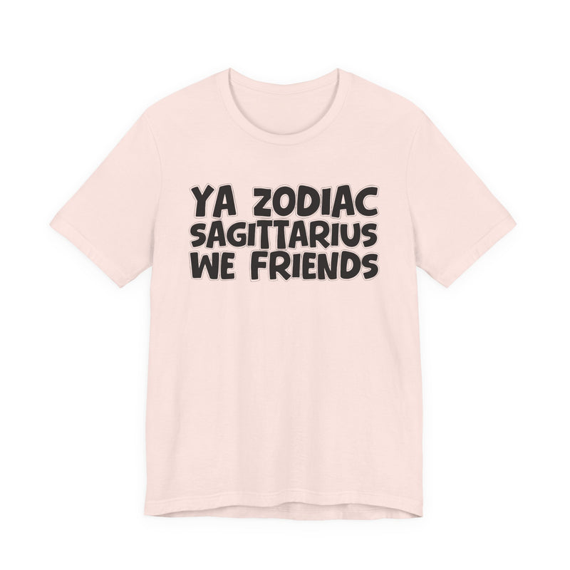 Soft Pink t-shirt with black 'YA ZODIAC SAGITTARIUS WE FRIENDS' cartoon bubble lettering, front flat-lay view.