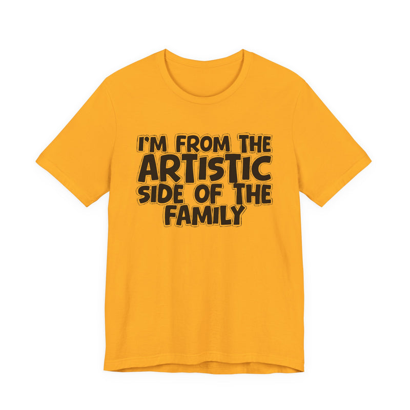 Black t-shirt with bold chest statement text reading 'I'M FROM THE ARTISTIC SIDE OF THE FAMILY,' front flat-lay view.