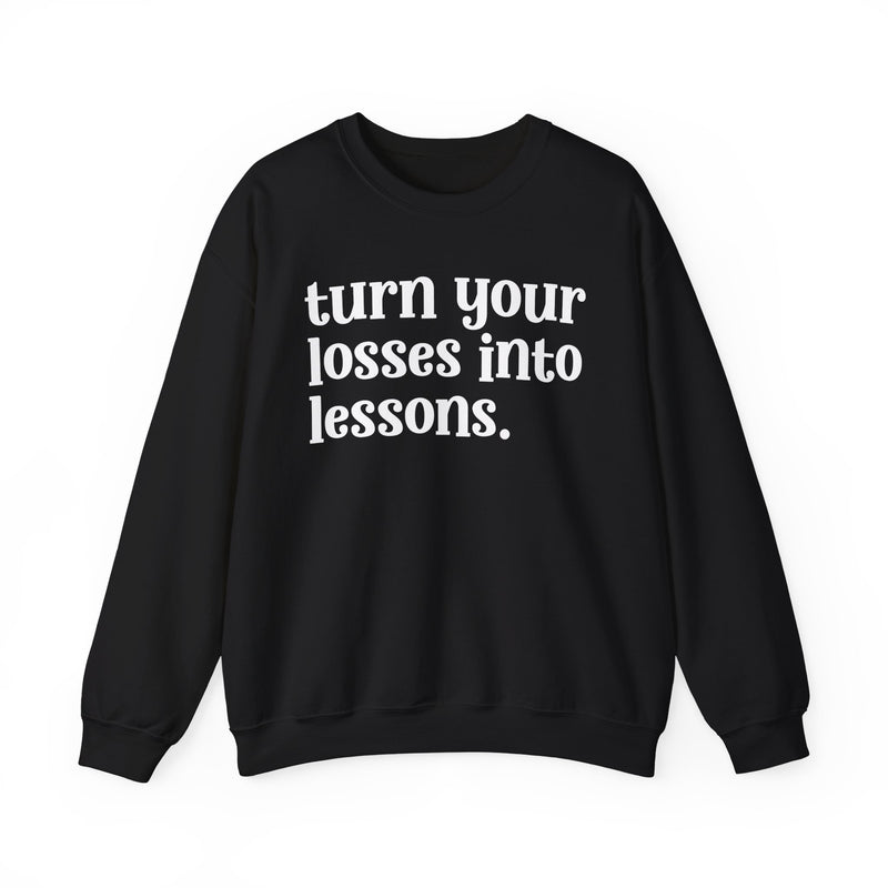 Black crewneck sweatshirt with white "turn your losses into lessons." lettering, front view.