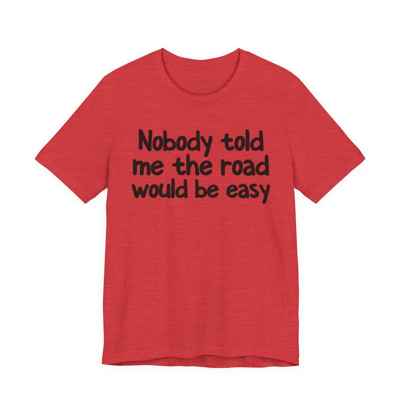 T-Shirt with text design reading “NOBODY TOLD ME THE ROAD WOULD BE EASY”, front view