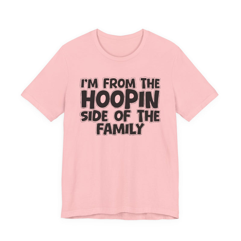 Pink t-shirt with white outlined bubble lettering reading 'I'M FROM THE HOOPIN SIDE OF THE FAMILY', front flat-lay view.