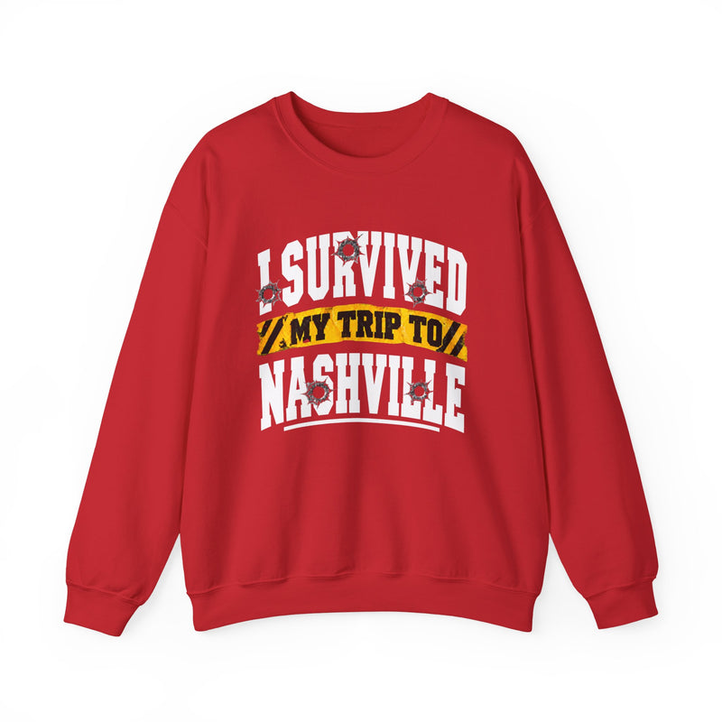 Red sweatshirt with white block lettering reading I SURVIVED MY TRIP TO NASHVILLE, with bullet-hole accents and a yellow caution-tape banner, front flat-lay view.