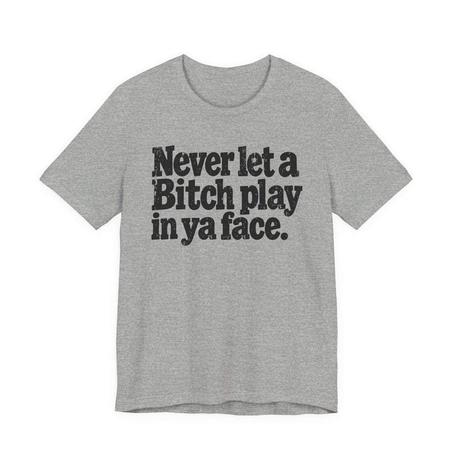 Graphic tee with bold statement lettering reading "NEVER LET A BITCH PLAY IN YA FACE", front view, product mockup
