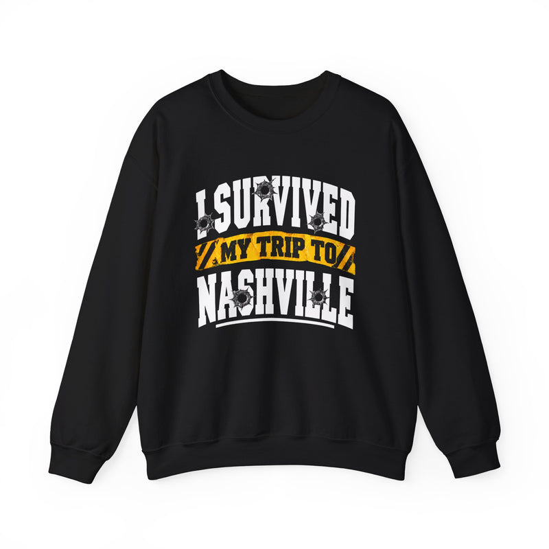 Black sweatshirt with white block lettering reading I SURVIVED MY TRIP TO NASHVILLE, with bullet-hole accents and a yellow caution-tape banner, front flat-lay view.