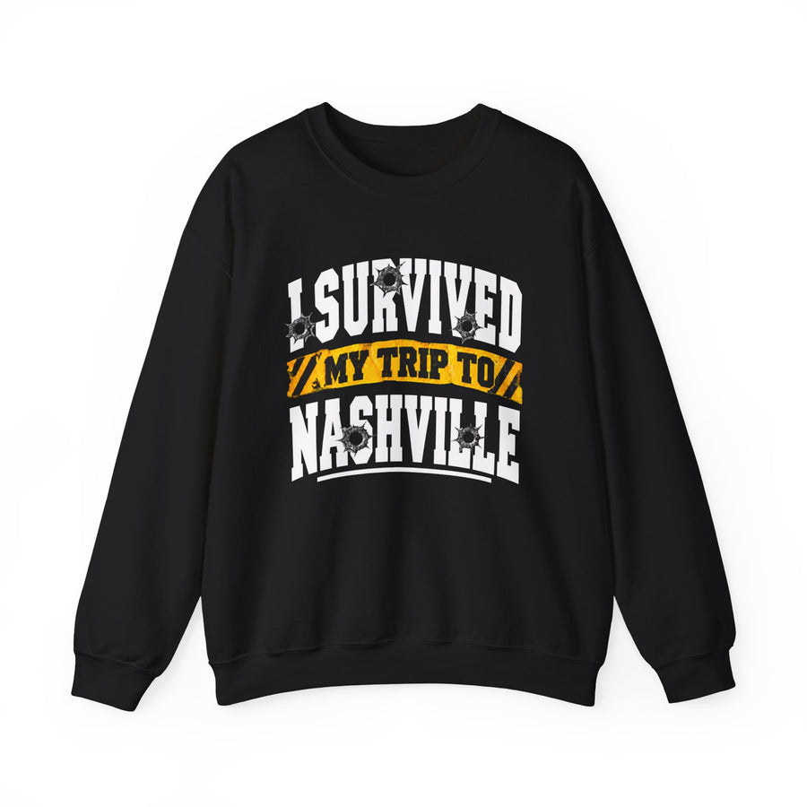 Black sweatshirt with white block lettering reading I SURVIVED MY TRIP TO NASHVILLE, with bullet-hole accents and a yellow caution-tape banner, front flat-lay view.