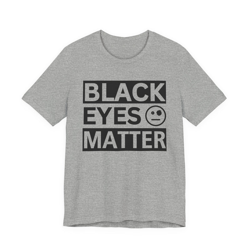 Athletic Heather t-shirt with ‘BLACK EYES MATTER’ in boxed block lettering with a smiley-face eye icon graphic in dark-contrast print, front flat-lay mockup view