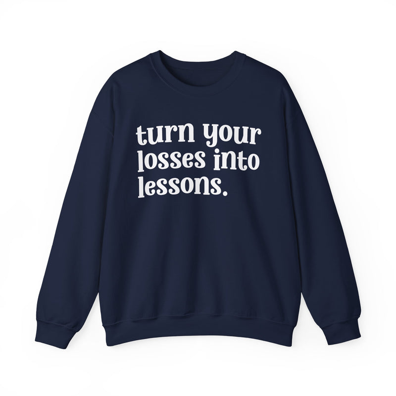 Navy crewneck sweatshirt with white "turn your losses into lessons." lettering, front view.