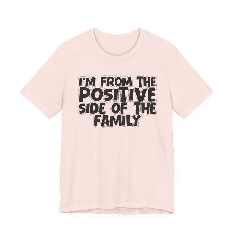 Soft Pink t-shirt with white outlined bubble lettering reading 'I'M FROM THE POSITIVE SIDE OF THE FAMILY', front flat-lay view.