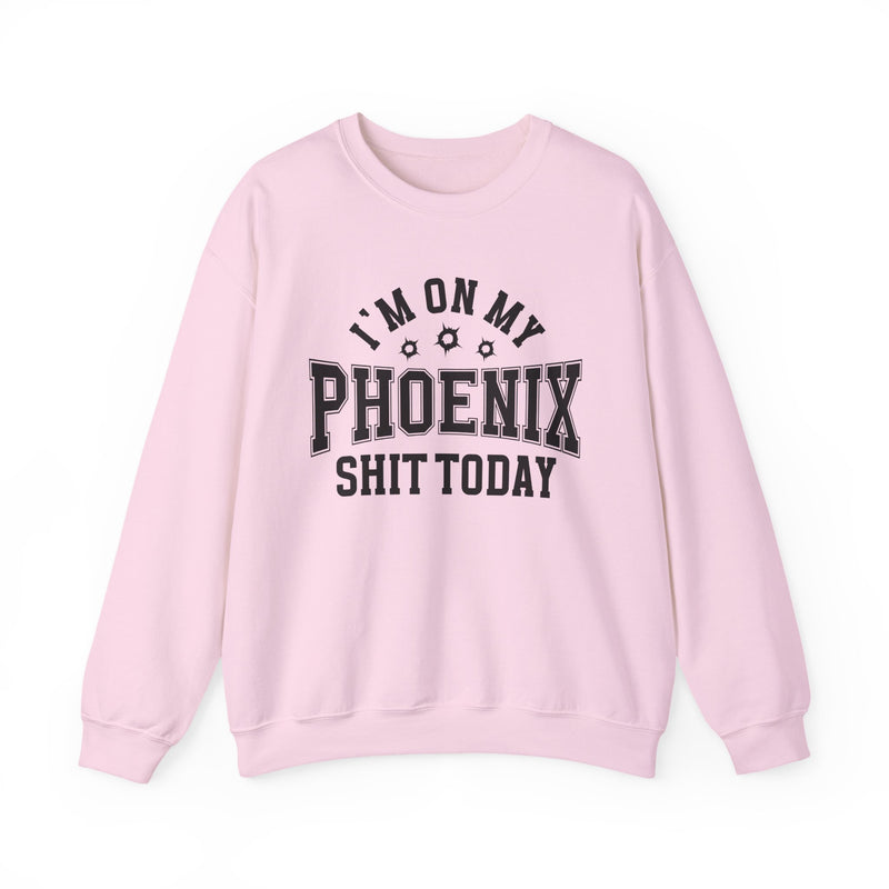 Light pink sweatshirt with black varsity block lettering reading I'M ON MY PHOENIX SHIT TODAY, with bullet-hole accents, front flat-lay view.