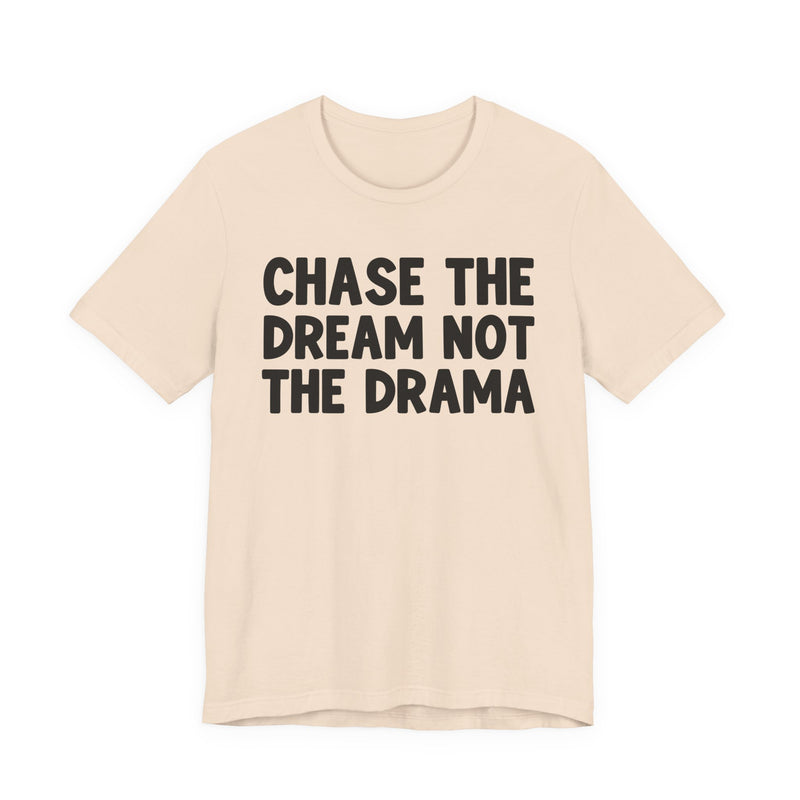 Natural t-shirt with black bold statement lettering reading CHASE THE DREAM NOT THE DRAMA, front flat-lay view.