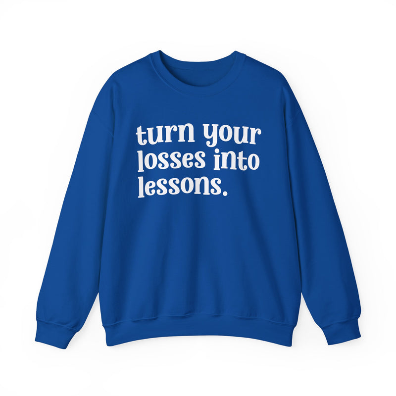 Royal blue crewneck sweatshirt with white "turn your losses into lessons." lettering, front view.