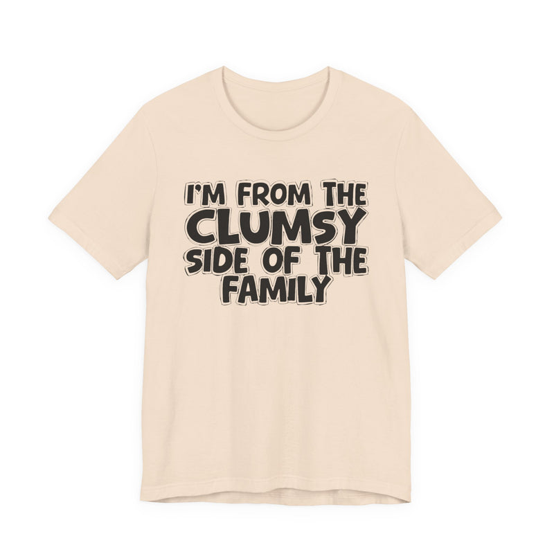 Soft Cream t-shirt, printed with the "I'M FROM THE CLUMSY SIDE OF THE FAMILY" statement in bold outlined bubble lettering, front flat-lay view.