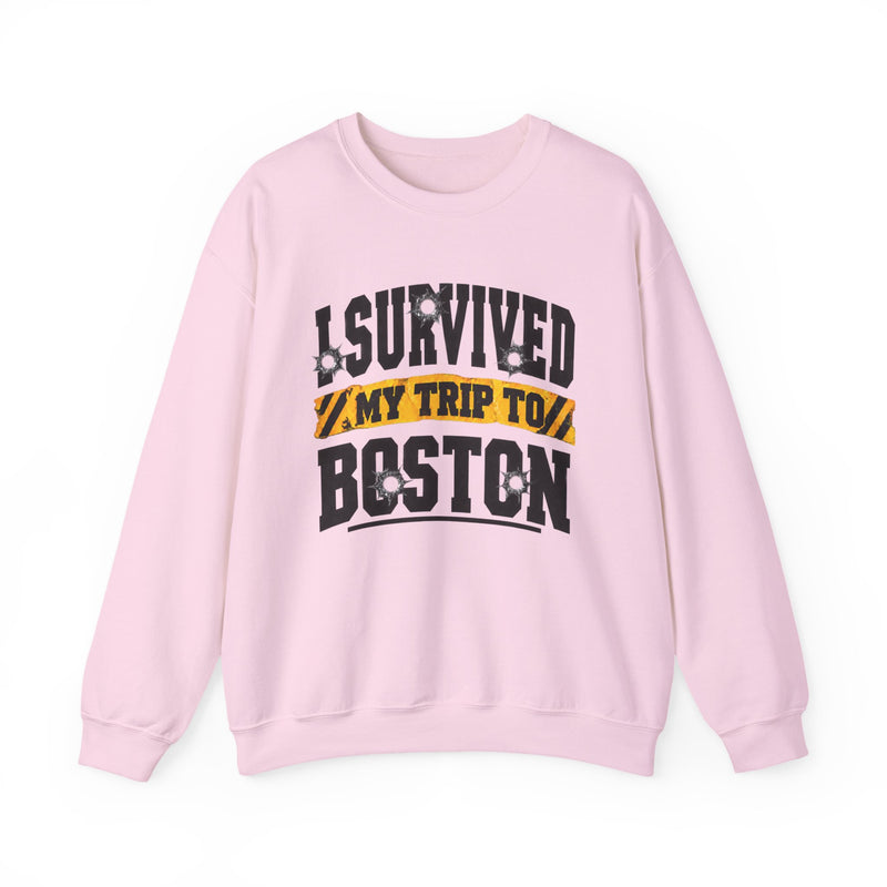 Light pink sweatshirt with black block lettering reading I SURVIVED MY TRIP TO PHOENIX, with bullet-hole accents and a yellow caution-tape banner, front flat-lay view.