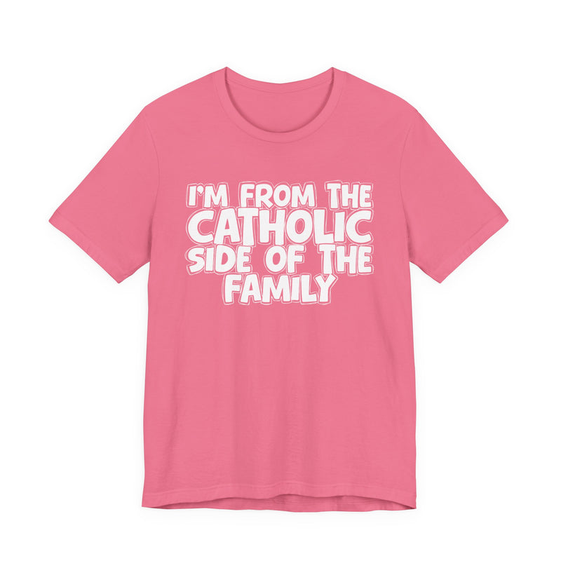 Charity Pink t-shirt with white outlined bubble lettering reading 'I'M FROM THE CATHOLIC SIDE OF THE FAMILY', front flat-lay view.