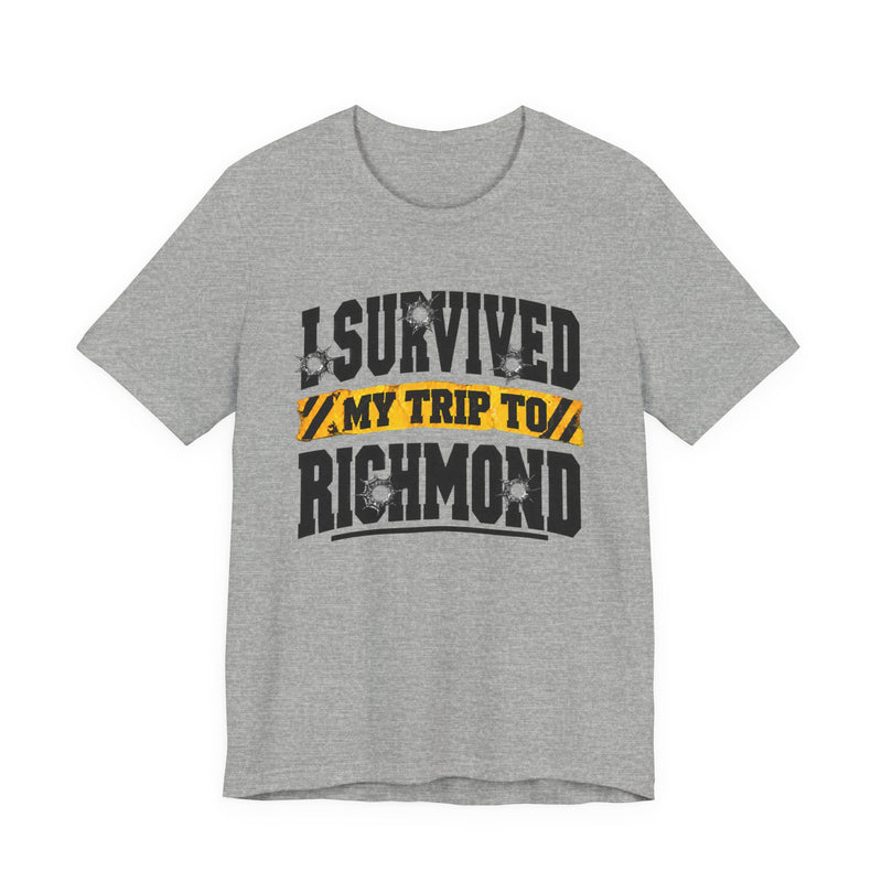 T-Shirt product photo with arched collegiate lettering reading "I SURVIVED" with bullet-hole decals, a caution-tape band reading "MY TRIP TO", and large block letters reading "RICHMOND", front view.