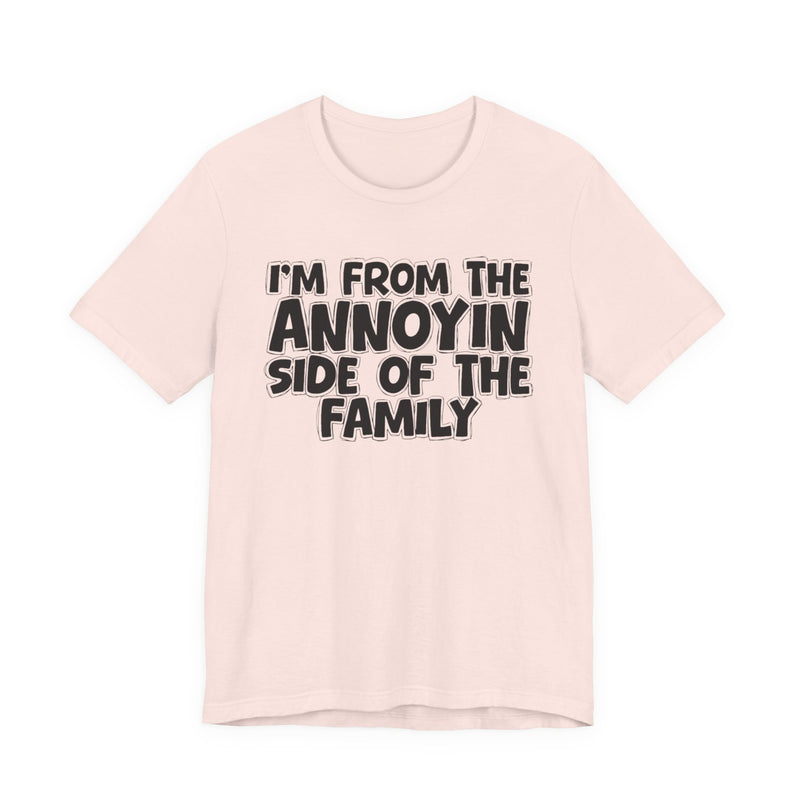 light t-shirt with ‘I’M FROM THE ANNOYIN SIDE OF THE FAMILY’ statement text in bold outline lettering, front flat-lay view.