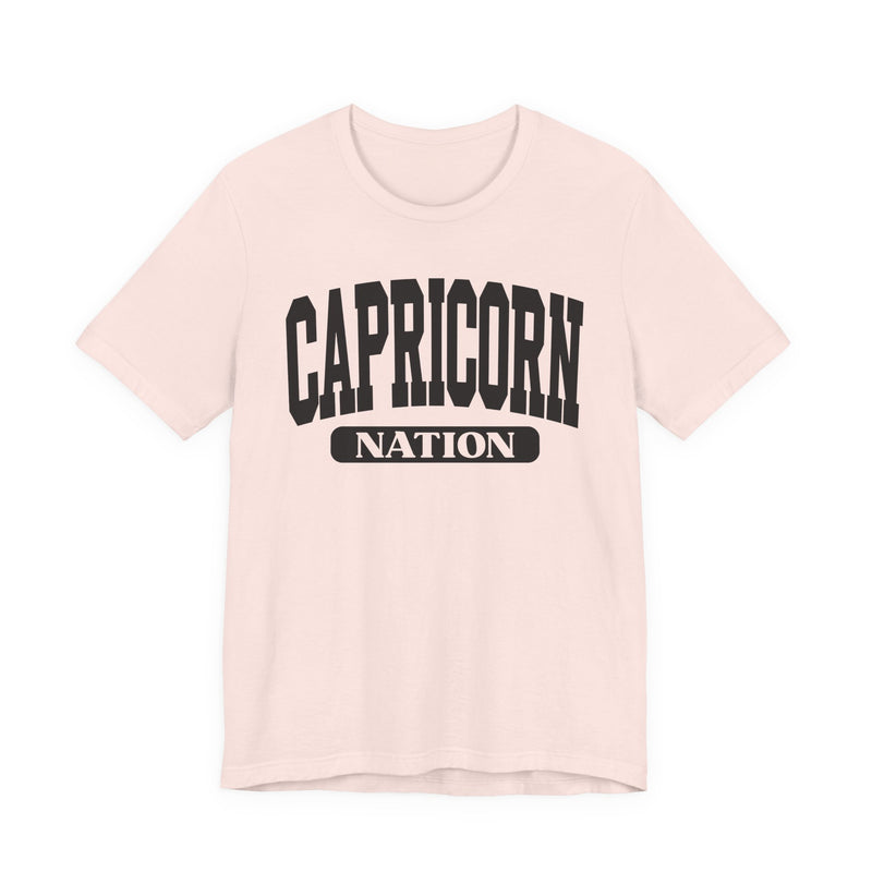 Soft Pink t-shirt with black arched CAPRICORN lettering and a NATION pill badge, front view.