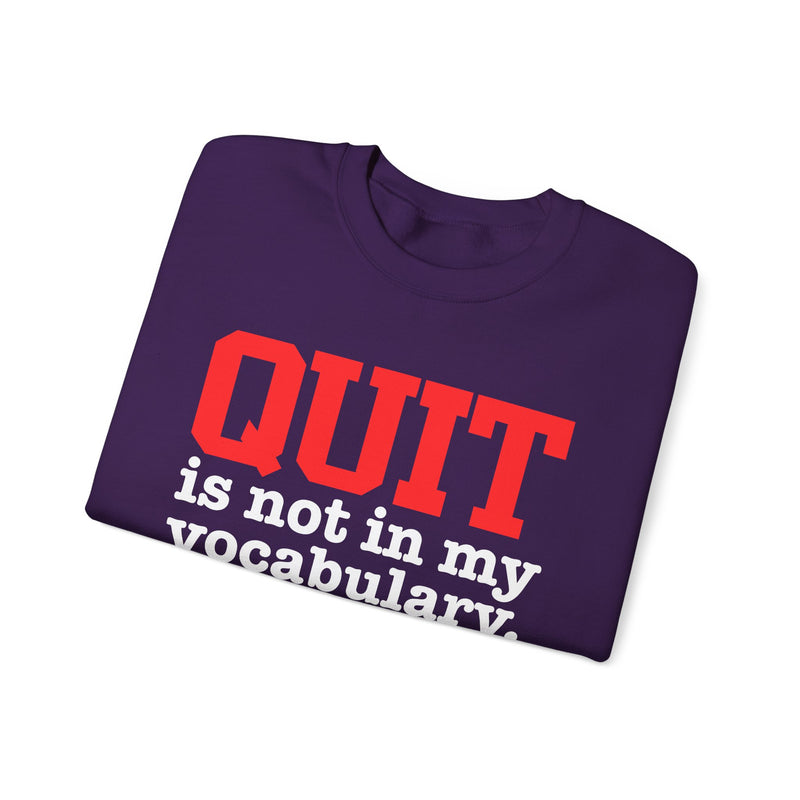 White sweatshirt with black block lettering with red accents reading "QUIT is not in my vocabulary.", front flat-lay view.